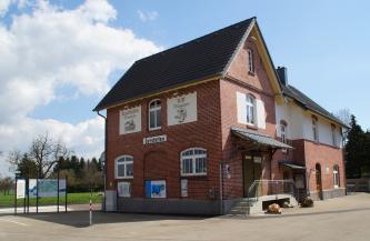 Blick auf das historische Bahnhofsgebäude in Gerstetten. Das mehrteilige Bauwerk beherbergt ein Riffmuseum sowie ein Eisenbahnmuseum. Rechts, im quergestellten Hauptgebäude, ist der überdachte Eingangsbereich mit kleiner Treppe zu sehen.