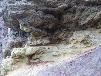 Nahaufnahme einer grauviolett bis graugelb gefärbten Gesteinsschicht, zerfurcht von tiefen Längsrinnen.