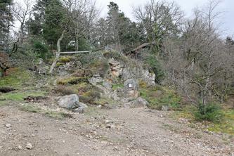 Das Quarzriff an der Sophienruhe mit Aussichtsplattform Blick auf einen nach rechts abfallenden steinigen Hang. Am oberen Ende des Hanges stehen Bäume. Dazwischen sind mehrere Felsen aufgeschichtet, auf denen sich eine Aussichtsplattform befindet.