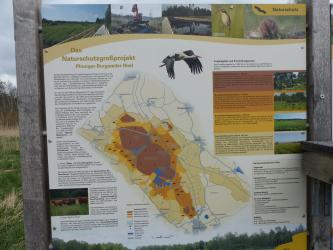 Auf dem Foto ist eine große Tafel abgebildet, mit Übersichtskarte und nützlichen Informationen zum Naturschutzgroßprojekt Pfrunger-Burgweiler-Ried.