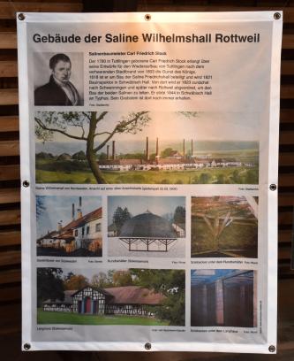Blick auf ein großes Plakat mit verschiedenen Bildern von Gebäuden der Saline Wilhelmshall in Rottweil. Auch der Baumeister Carl Friedrich Stock findet Erwähnung.