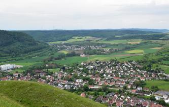 Blick vom Ipf nach Südwesten über Oberdorf und die Egeraue zum Albtrauf bei Bopfingen-Aufhausen Blick über die Kuppe eines Wiesenhanges auf eine flachwellige Auenlandschaft mit Wiesen, Äckern und Siedlungen. Links am Bildrand steigt ein bewaldeter Berg auf. Im Hintergrund begrenzen flachere, langgezogene Höhen die Aue.