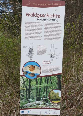 Informationstafel an der „Rauhen Wiese“ bei Böhmenkirch Blick auf eine schmale hohe farbige Schautafel mit Texten, Bildern und Zeichnungen zu den Themen Waldgeschichte sowie Eisenverhüttung. Die Tafel steht beim Naturerlebnis „Rauhe Wiese“ bei Böhmenkirch.
