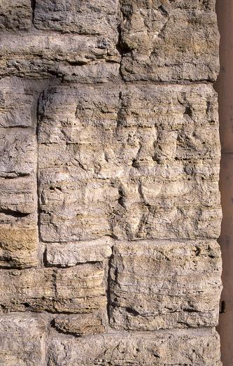 Das Foto zeigt mehrere neben- und aufeinander geschichtete Mauersteine. Die Steine sind waagerecht gefurcht und gelblich braun bis hellgrau gefärbt.