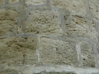 Nahaufnahme von grünlich grauen Mauersteinen, im Bogen von links nach rechts verlaufend, mit blasenartigen Ausformungen.